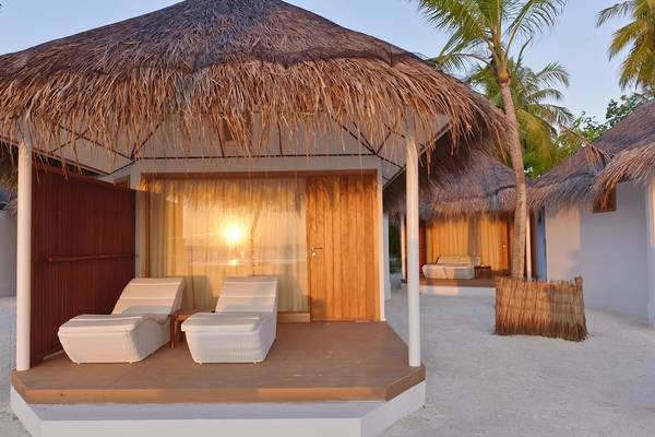 Außenbereich des Thulhagiri Island Resorts mit einer Hütte und Liegestühlen auf einer Holzterrasse.