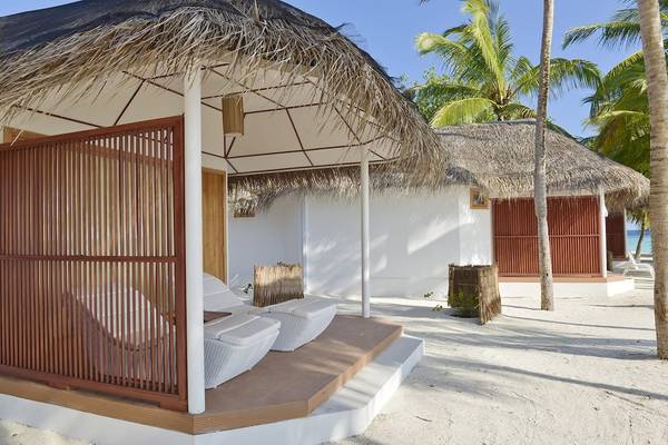 Thulhagiri Island Resort Strand Chalet mit weißen Liegestühlen und Strohdach