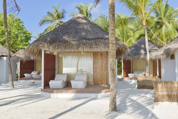 Außenbereich des Thulhagiri Island Resorts mit runden Strohhütten am Strand