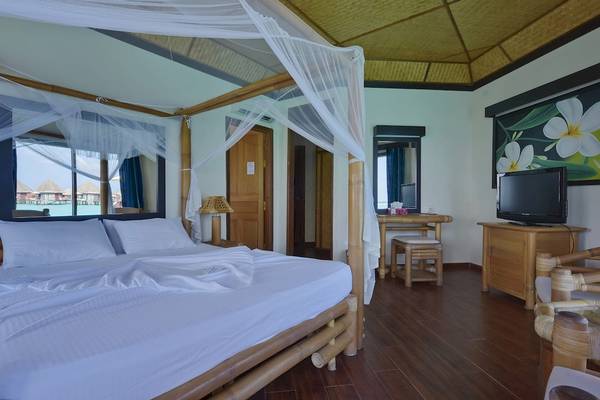 Ein Schlafzimmer im Thulhagiri Island Resort mit einem Bett, Fernseher und Blick auf das Meer.