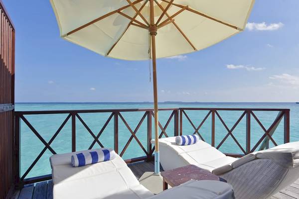 Balkon des Thulhagiri Island Resorts mit Liegen unter einem Sonnenschirm mit Blick auf den Ozean.