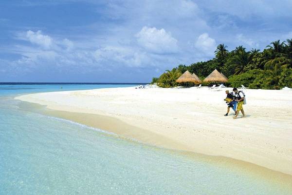 Thulhagiri Island Resort Strand mit zwei Tauchern und Palmenhütten im Hintergrund.