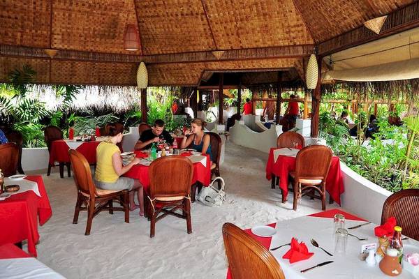 Innenansicht des Thulhagiri Island Resort Restaurants mit Gästen an Tischen und Pflanzen im Hintergrund.