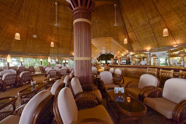 Innenbereich der Thulhagiri Island Resort Lounge mit gepolsterten Stühlen und Tischen, einer Bar und Holzdecken.