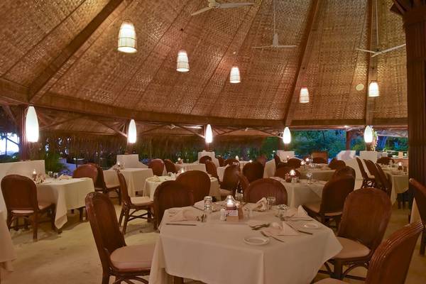 Innenansicht des Restaurants im Thulhagiri Island Resort mit mehreren gedeckten Tischen und Stühlen.