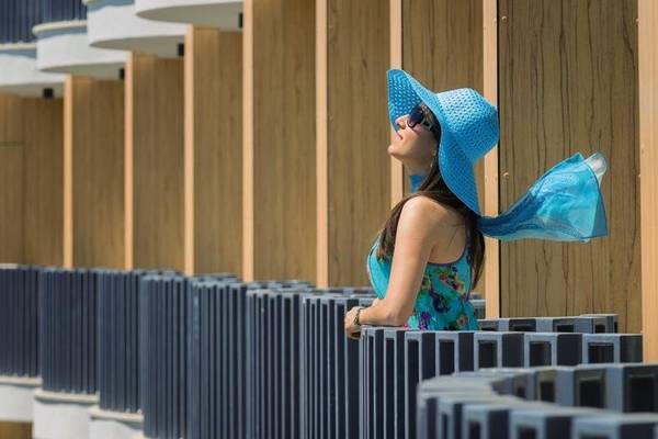Eine Frau im HVD Club Bor Hotel steht vor einer blauen Wand und schaut in den Himmel.