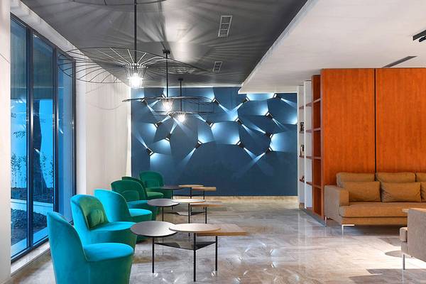 Lobby des HVD Club Bor Hotels mit blauen und grünen Stühlen, runden Tischen und einem großen Sofa.