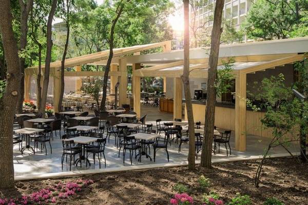 Terrasse des HVD Club Bor Hotels mit Tischen, Stühlen und Bäumen.
