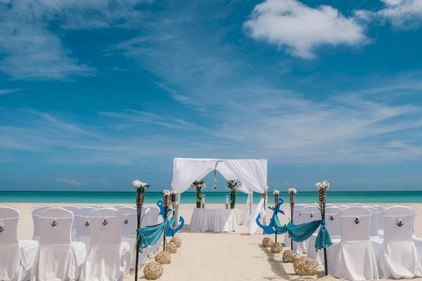 Hochzeitszeremonie am Strand des Iberostar Selection Varadero Hotels mit weißen Stühlen und blauen Dekorationen.