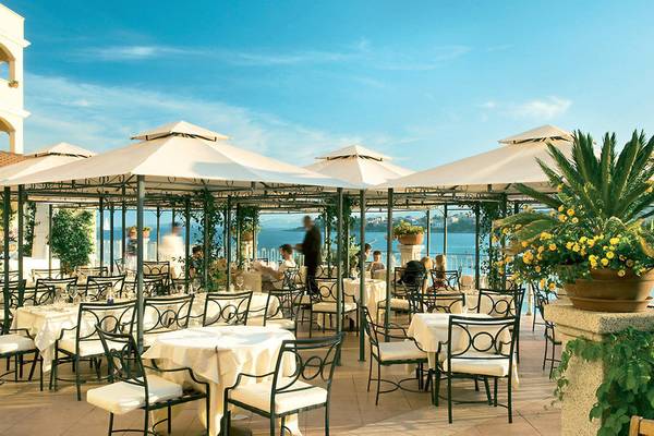 Terrasse des Gabbiano Azzurro Hotel & Suites mit Tischen und Sonnenschirmen