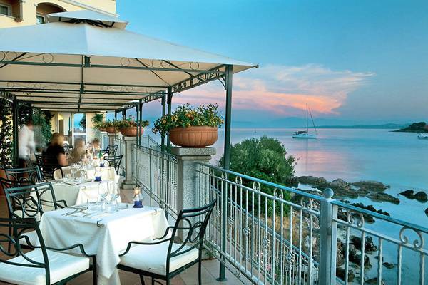 Terrasse des Gabbiano Azzurro Hotel & Suites mit Blick auf das Meer und eine Segelyacht.