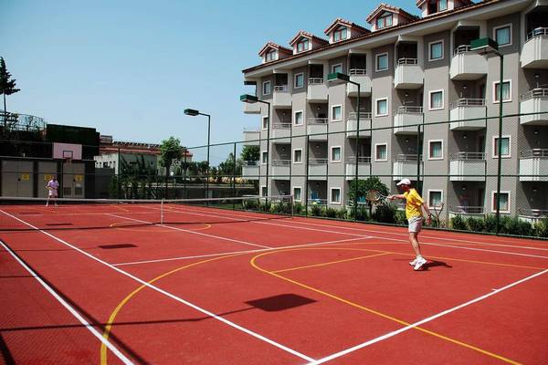 Tennisplatz vor dem Monachus Hotel & Spa mit zwei Spielern und einem Gebäude im Hintergrund.