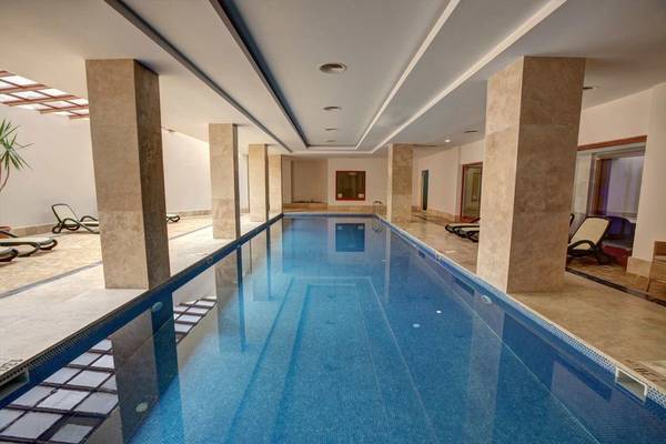 Innenpool des Monachus Hotel & Spa mit geometrischen Säulen und Lounge-Liegestühlen