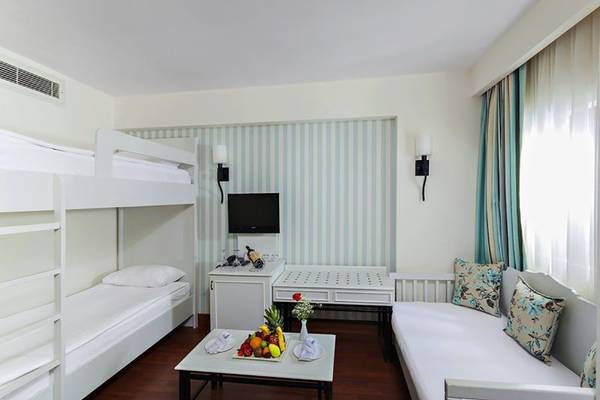 Schlafzimmer im Monachus Hotel & Spa mit zwei Etagenbetten, Fernseher, Tisch mit Früchten und Deko auf dem Boden.