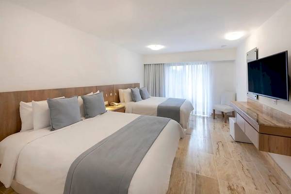 Hotelzimmer von Viva Wyndham Dominicus Palace mit zwei Betten, Fernseher und Nachttisch.
