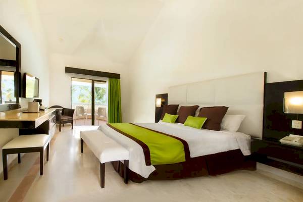 Schlafzimmer im Viva Wyndham Dominicus Palace Hotel mit grüner Bettwäsche und Balkon.