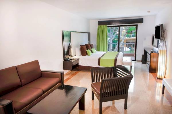 Innenansicht eines Zimmers im Viva Wyndham Dominicus Palace mit Bett, Sofa und Möbeln.