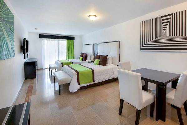 Innenansicht eines Hotelzimmers im Viva Wyndham Dominicus Palace mit zwei Betten, Tisch und Stühlen.