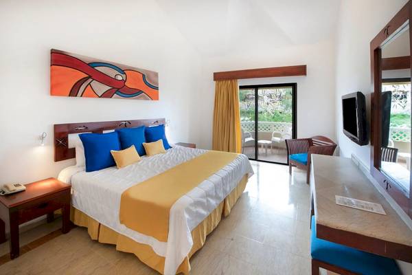 Innenansicht eines Hotelzimmers im Viva Wyndham Dominicus Palace mit einem großen Bett und einer Terrasse.