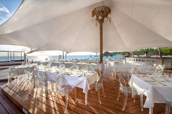 Viva Wyndham Dominicus Palace Strandrestaurant mit vielen Tischen und Stühlen unter einem großen weißen Dach.