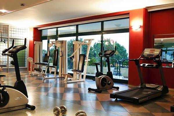 Fitnessraum im Miramare Beach Hotel mit verschiedenen Trainingsgeräten und Blick auf die Außenanlagen.