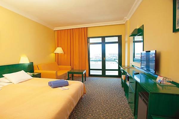 Doppelbettzimmer im Miramare Beach Hotel mit gelben Wänden, grüner Einrichtung und Meerblick.