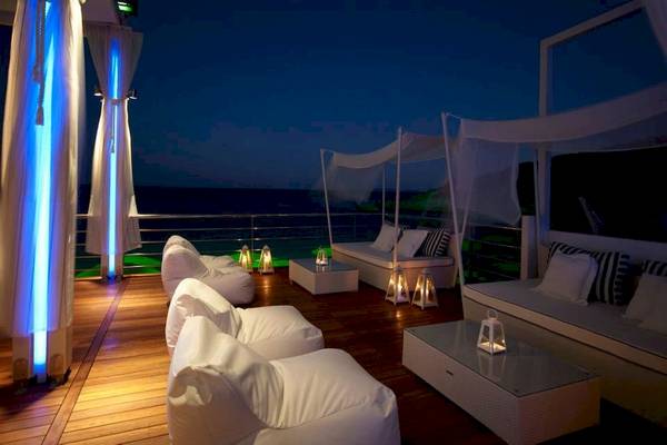 Abendlounge des Proteas Blu Resorts mit beleuchteten Vorhängen und Blick auf den Ozean.