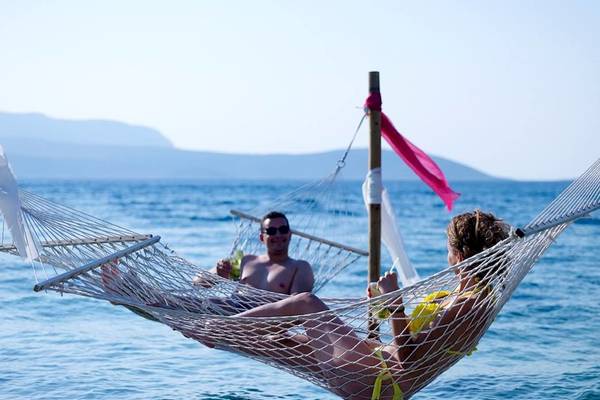 Paar im Proteas Blu Resort, das in Hängematten im Meer sitzt.