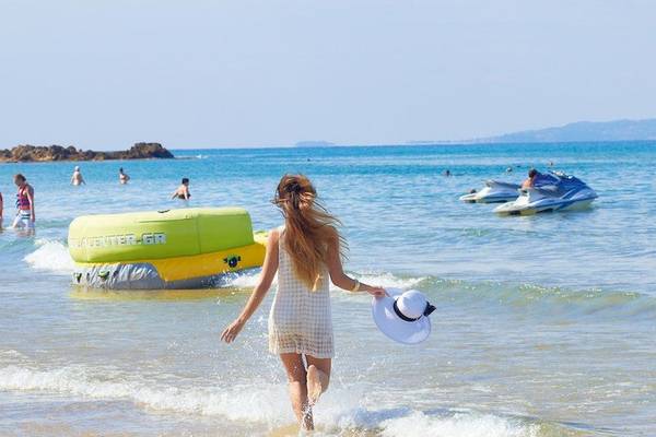 Griechenland Urlaub am Strand mit Wasserrutschen und Jetskis im Hintergrund.