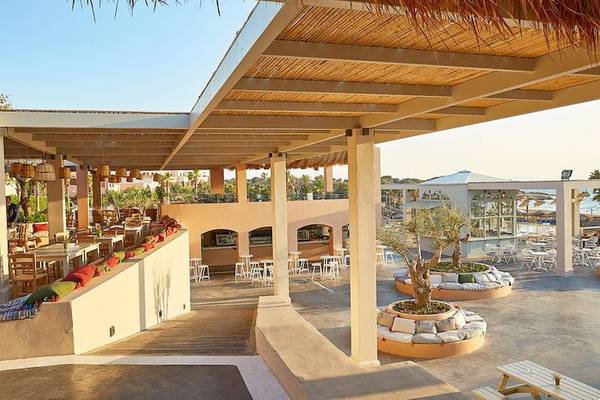 Außenbereich des Grecotel Olympia Oasis Aqua Park mit Tischen und Stühlen unter einem Dach