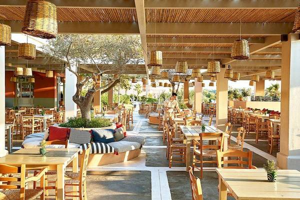 Innenansicht des Restaurants im Grecotel Olympia Oasis Aqua Park mit Holztischen und Stühlen.