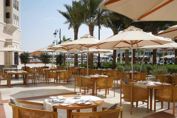Terrasse des Ritz Carlton Abu Dhabi Grand Canal Hotels mit Tischen und Stühlen unter Schirmen