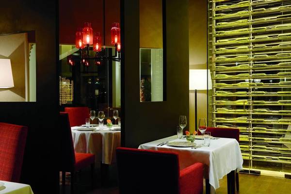 Innenansicht des Ritz Carlton Abu Dhabi Grand Canal Restaurants mit gedeckten Tischen und roten Stühlen.