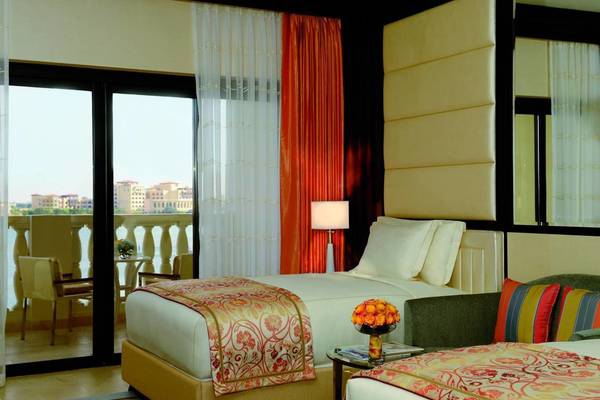 Zimmer im Ritz Carlton Abu Dhabi Grand Canal mit zwei Betten, einem Sofa und einem Ausblick auf die Stadt.