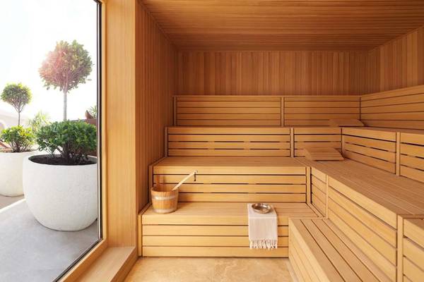 Innenansicht einer Sauna im Ritz Carlton Abu Dhabi mit Holzbänken, einem Eimer und einem Handtuch.