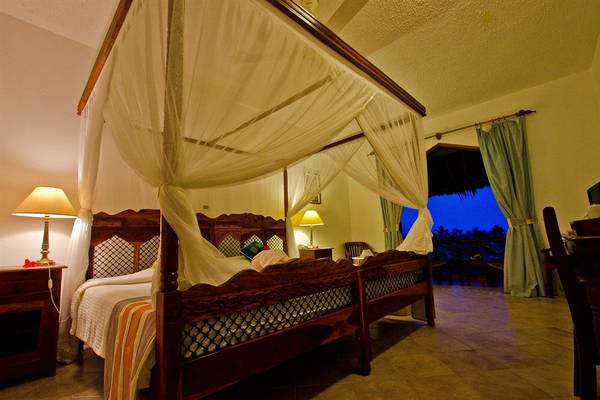 Doppelbett mit Baldachin im Bluebay Beach Resort & Spa mit Blick auf den nächtlichen Himmel.