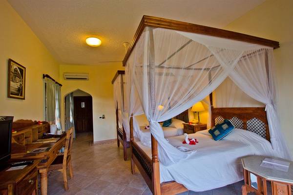 Schlafzimmer im Bluebay Beach Resort & Spa mit zwei Himmelbetten, einem Schreibtisch und einem Fernseher.