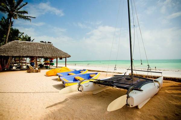 Strandszene mit Booten und Sonnenschirm am Bluebay Beach Resort & Spa