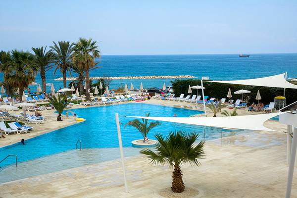 Poolbereich des Venus Beach Hotels mit Sonnenschirmen und Liegen am Meer