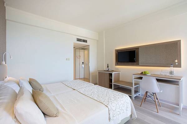 Schlafzimmer im Venus Beach Hotel mit Doppelbett, Schreibtisch und Fernseher.
