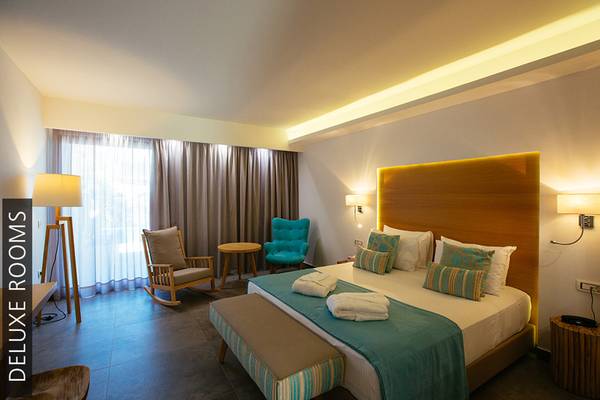 Luxus Zimmer im Aphrodite Beach Club mit großem Bett, Kissen, und blauem Bettlaken.