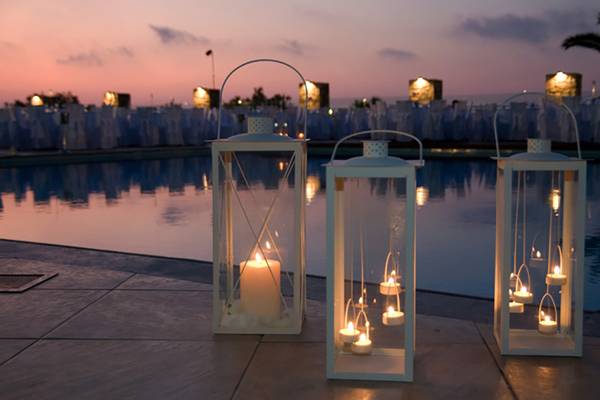 Drei Laternen am Pool des Aphrodite Beach Clubs bei Nacht, mit Kerzen und einem Blick auf den Horizont.