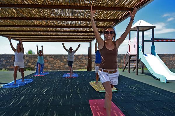 Gruppe von Menschen, die Yoga auf Matten unter einer Pergola im Aphrodite Beach Club praktizieren