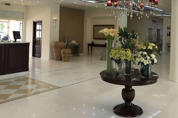 Empfangsbereich des Aphrodite Beach Club Hotels mit einem zentralen Blumenarrangement auf einem runden Tisch.