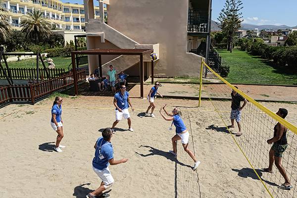 Mehrere Personen spielen Volleyball auf dem Sandplatz des Aphrodite Beach Clubs.