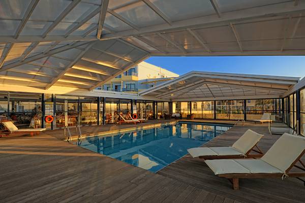 Innenpoolbereich des Aphrodite Beach Club mit Sonnenliegen und Glaswänden.