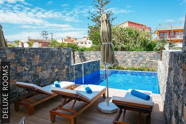 Deluxe Zimmer am Pool des Aphrodite Beach Clubs mit Sonnenliegen und Sonnenschirm.