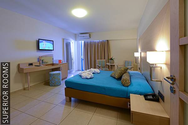Innenansicht eines Superior Zimmers im Aphrodite Beach Club mit Bett, Fernseher, Schreibtisch und Möbeln.