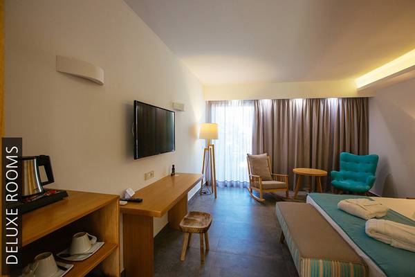 Deluxe Zimmer im Aphrodite Beach Club mit Fernseher, Schreibtisch, Sesseln und Bett.