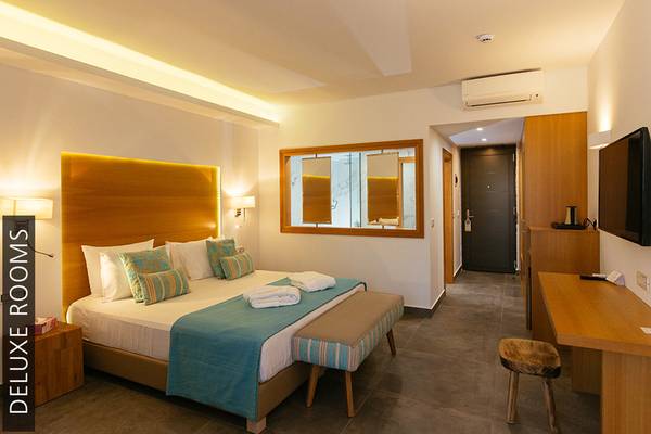 Ein luxuriöses Zimmer im Aphrodite Beach Club Hotel mit Doppelbett, Dekor und modernen Annehmlichkeiten.